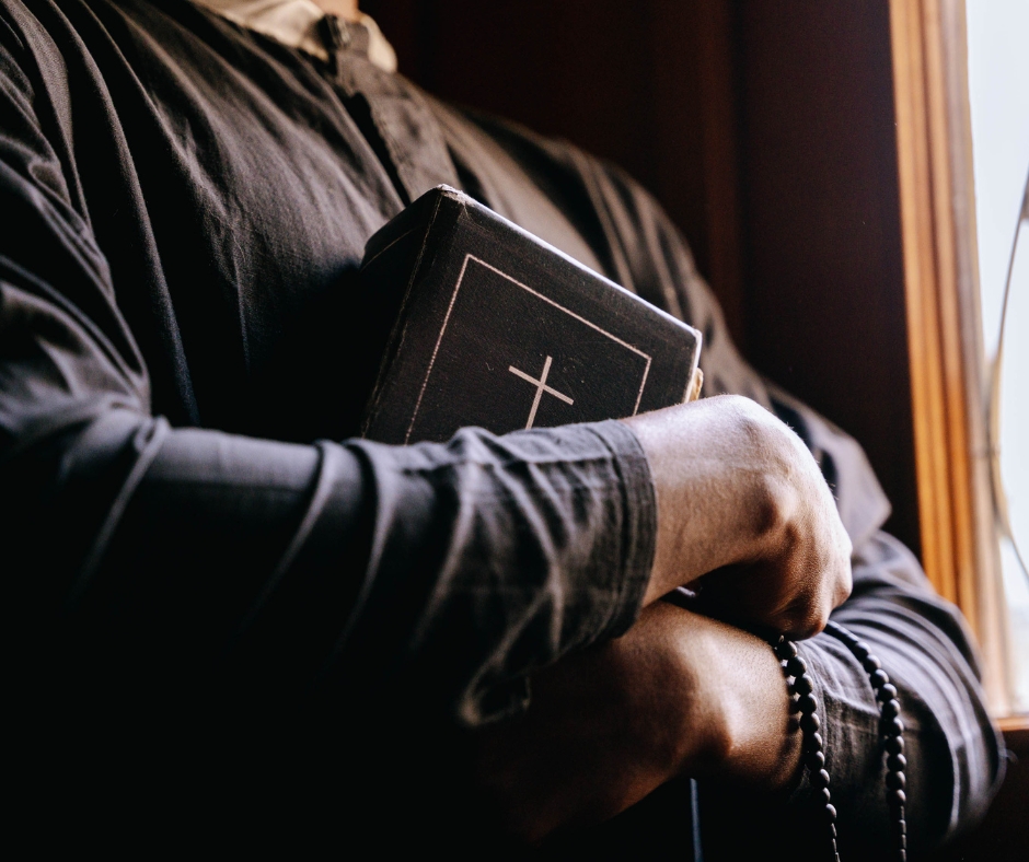 priest holding a bible while in a catholic church